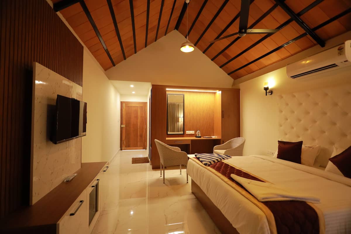 A modern hotel room with a large bed, a desk, a television, and an air conditioning unit.