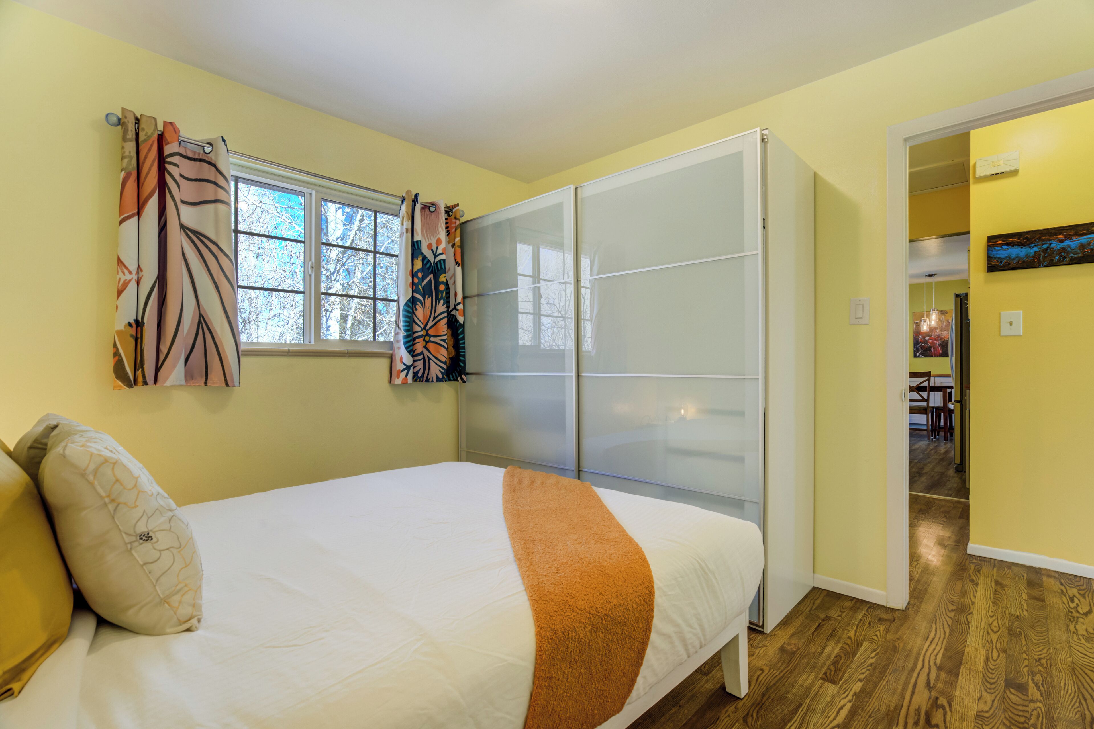 Ein Schlafzimmer mit Bett, Kleiderschrank und einem fensterbepflanzten Fenster.