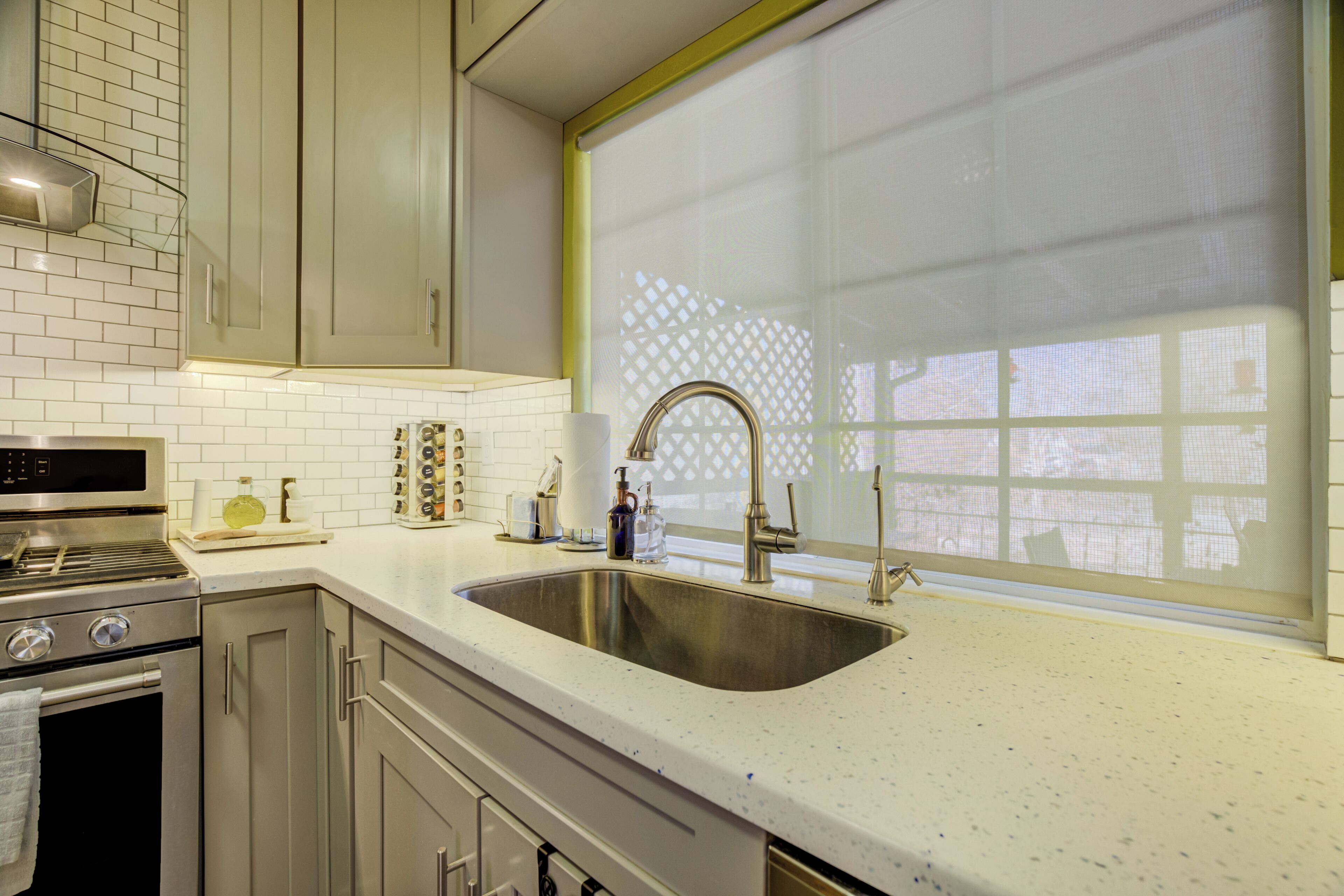 A kitchen with stainless steel appliances, a double sink, and a window with a decorative screen.