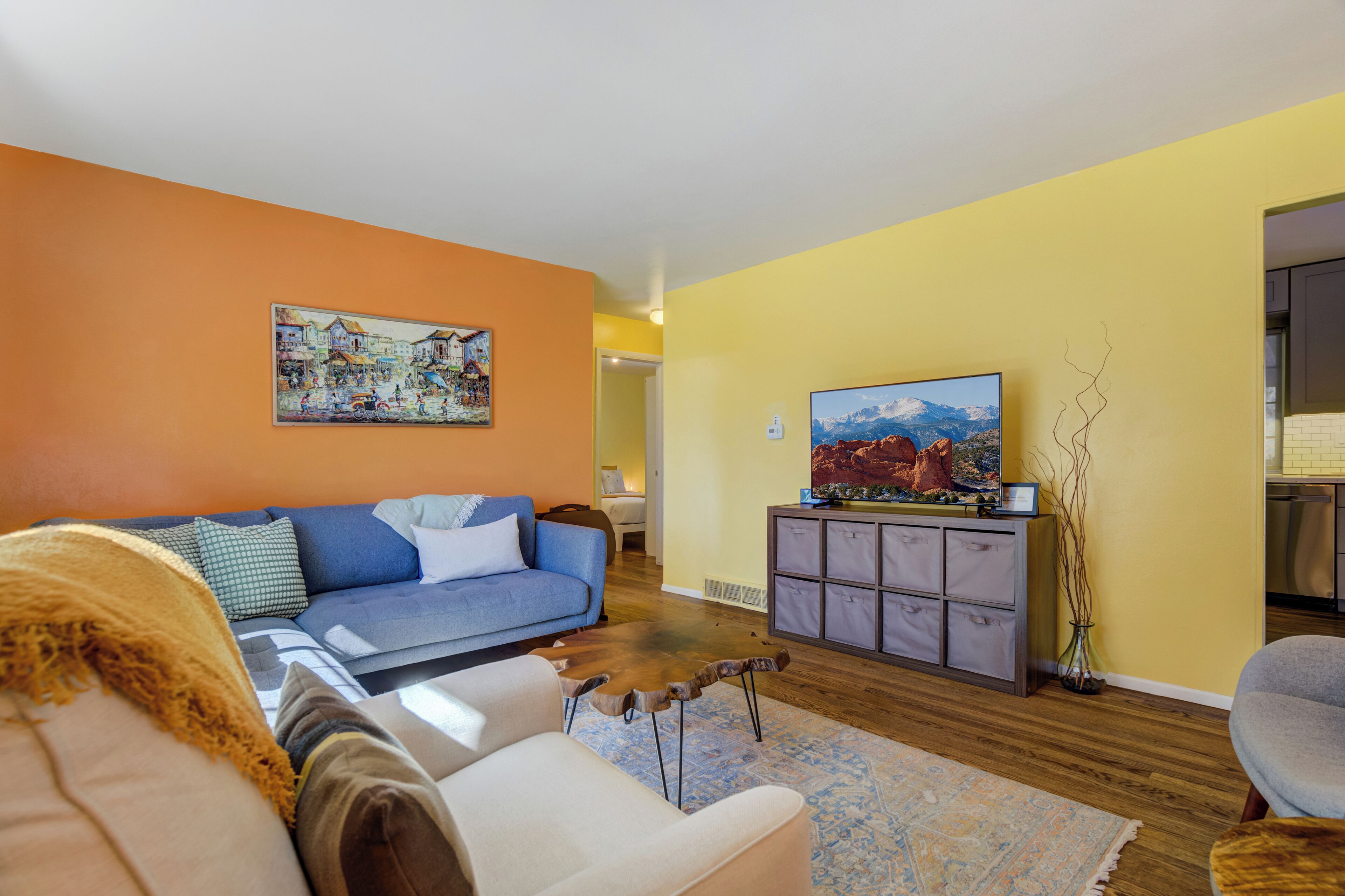 A living room with a blue sofa, a wooden coffee table, and a painting on the wall.