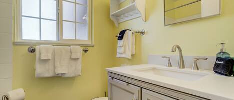 A bathroom with a toilet, sink, mirror, and towel rack.