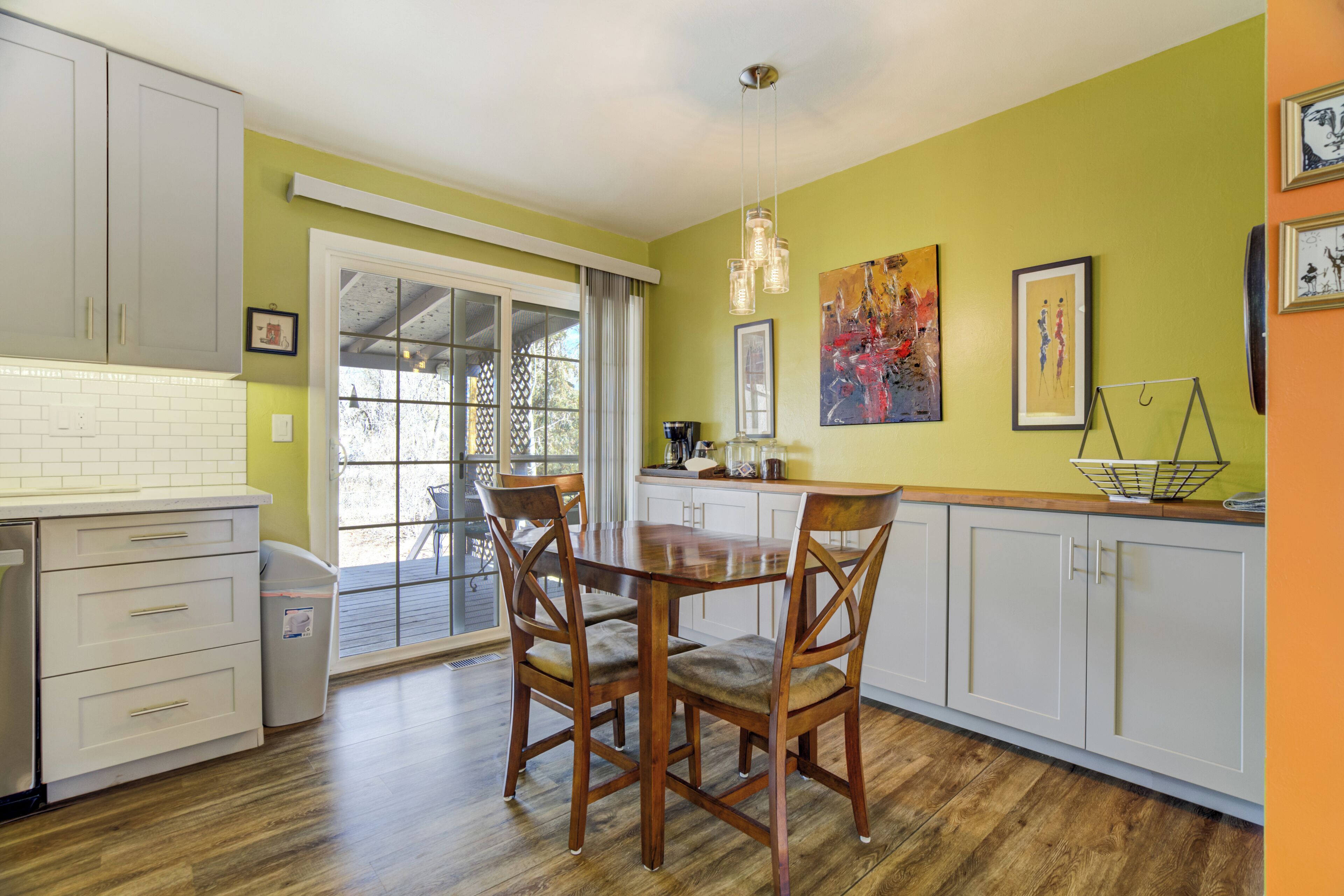 A kitchen with white cabinets, a wooden dining table, and chairs.