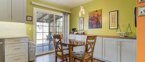 A kitchen with white cabinets, a wooden dining table, and chairs.