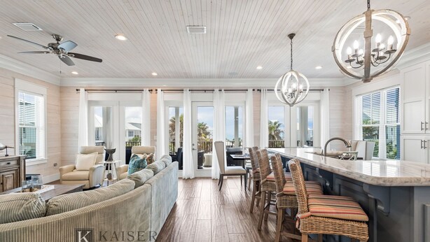 A spacious living area with a large sofa, a dining table, and a kitchen island with bar stools. - Welcome to Tide and True | New Luxury Beachfront Retreat | Cottages at Romar 17 (Orange Beach)