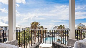 A balcony with wicker furniture and a view of a swimming pool. - Welcome to Tide and True | New Luxury Beachfront Retreat | Cottages at Romar 17 (Orange Beach)