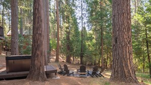 Waldlandschaft mit Whirlpool, Holzterrasse und Sitzgelegenheit im Freien.