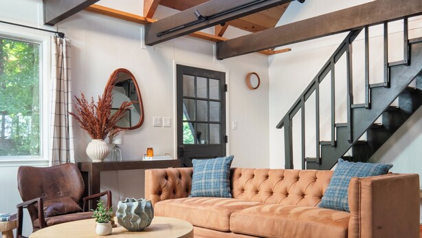 Ein gemütliches Wohnzimmer mit Holzboden, einer Couch, einem Couchtisch und einer Treppe.