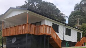 Une maison moderne de plain-pied, dotée d’une terrasse en bois et d’un porche couvert.