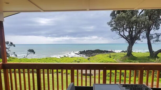 Une terrasse en bois offrant une vue sur l’océan et le rivage rocheux.