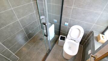 A modern bathroom with a glass-enclosed shower, a toilet, and a bidet.
