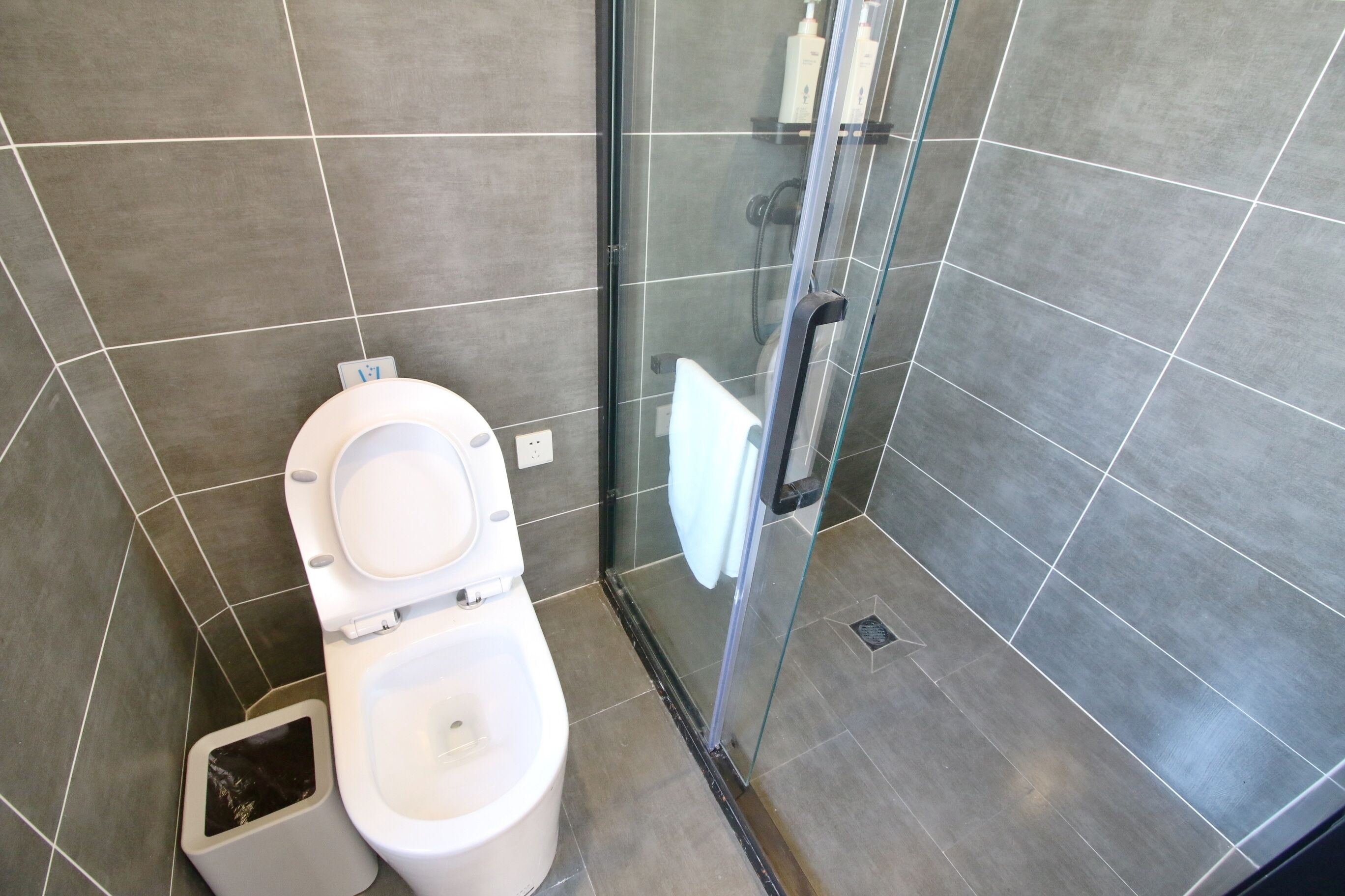A modern bathroom with a toilet, shower, and glass-enclosed shower area.