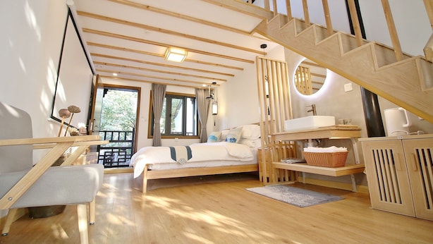 A bedroom with a wooden staircase, a bed, a desk, and a window with curtains. - shierpusu (Shaoxing)