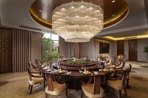 A formal dining room with a large chandelier, round table, and multiple chairs.