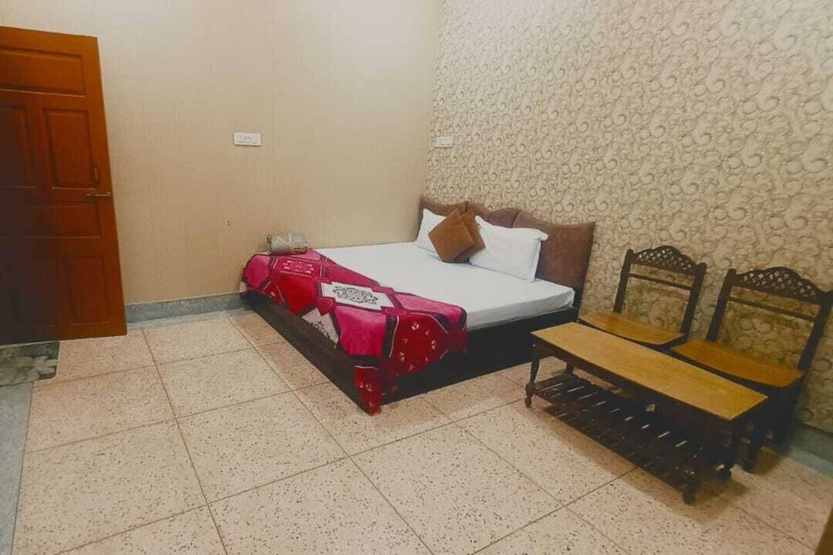 A bedroom with a bed, a bench, and a patterned wall.