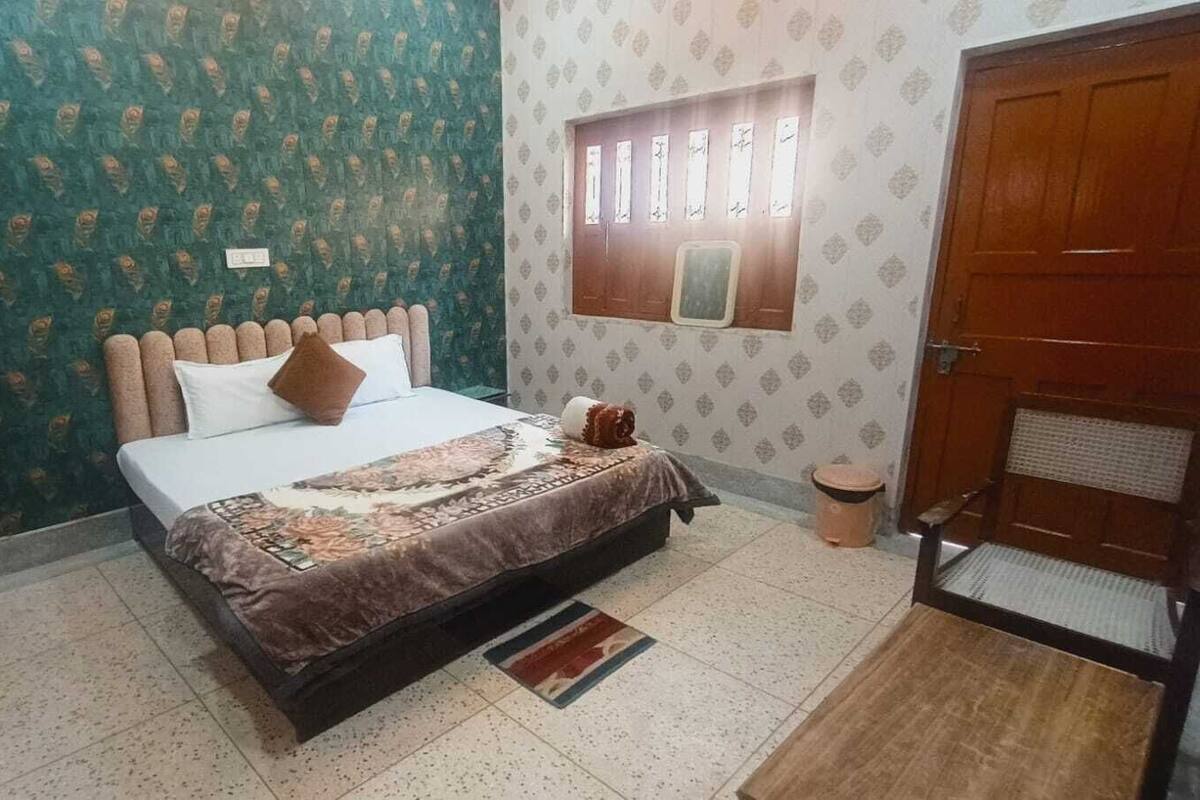 A bedroom with a bed, a window with curtains, a door, and a patterned wall.