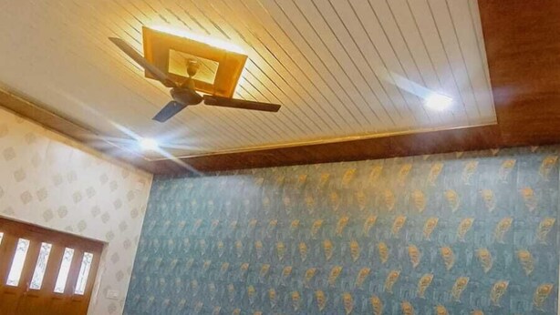 A bedroom with a bed, a ceiling fan, and a patterned wall. - Shree p Guest House (Varanasi)