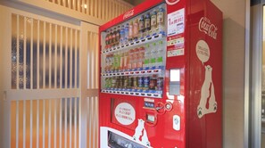 A red Coca-Cola vending machine with multiple beverage options and a payment terminal.
