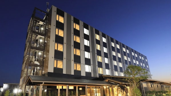 A multi-story hotel with a modern design, featuring a prominent fire escape on the left side and a well-lit entrance.