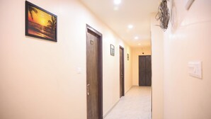 A hallway with doors numbered 102 and 103, a framed picture on the wall, and a light switch on the right. - Hotel Kalpana (Patna)