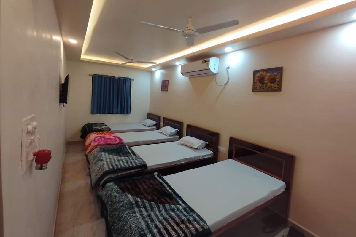 A hotel room with three single beds, a ceiling fan, an air conditioning unit, and a sunflower painting on the wall.