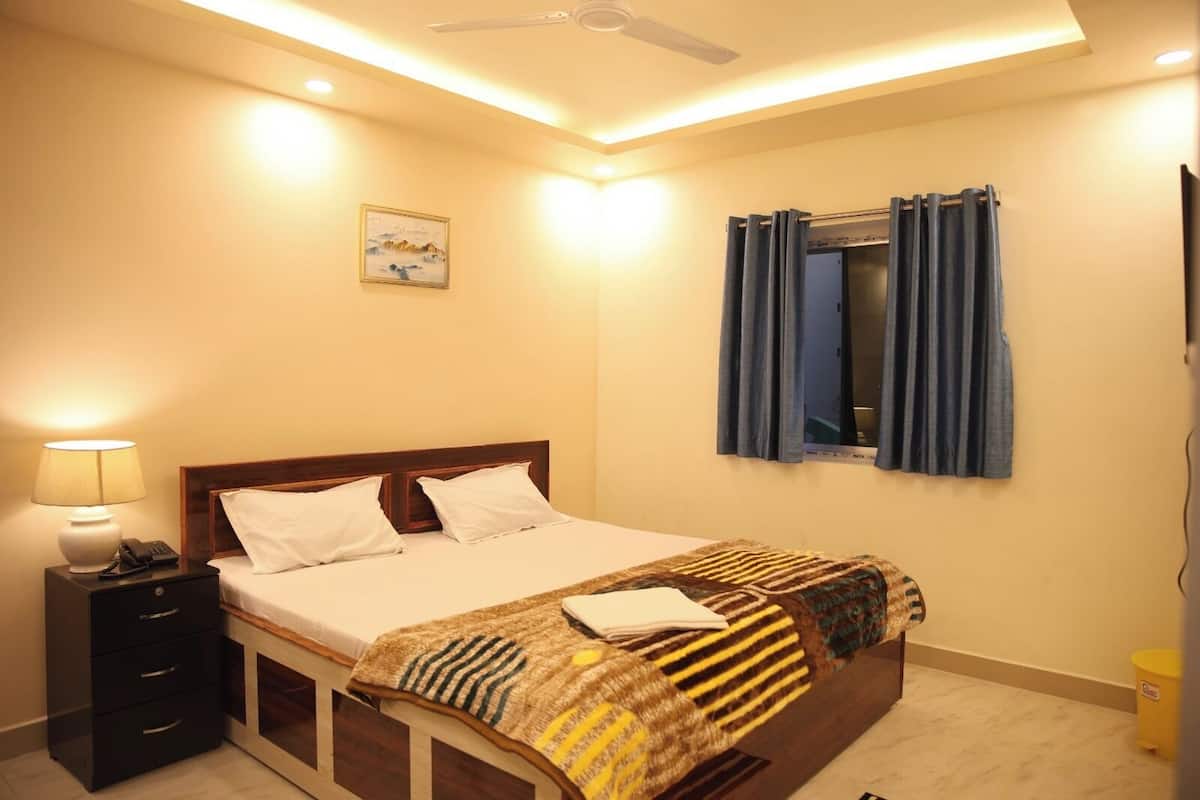 A bedroom with a bed, bedside table, lamp, and a window with curtains.
