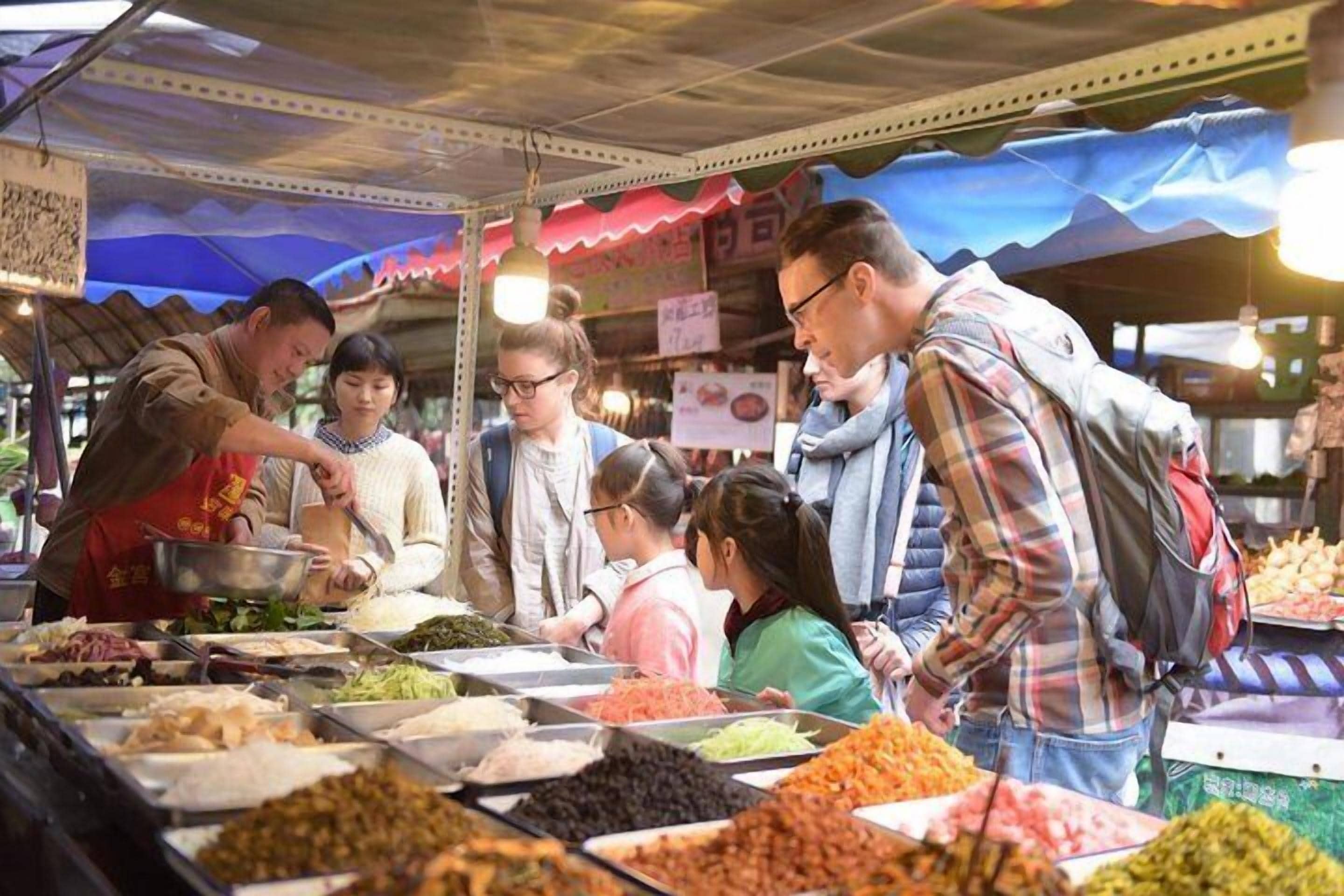 Een kraam op een markt met verschillende etenswaren en mensen die met elkaar praten.