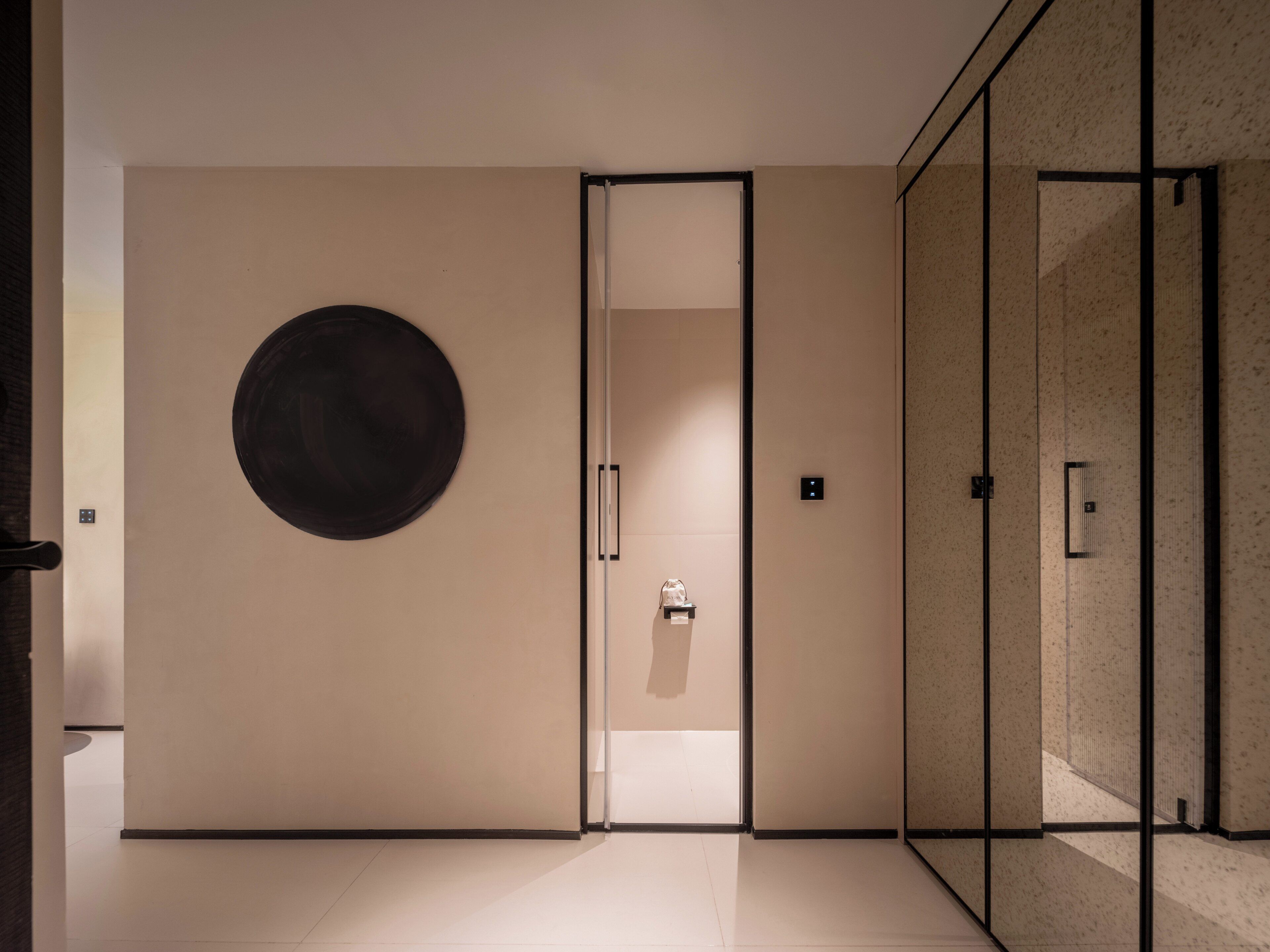 A modern interior with a minimalist design, featuring a large circular artwork on the wall, a glass partition, and a clean, uncluttered space.