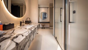 Une salle de bain moderne avec un meuble-lavabo en marbre, un grand miroir et une zone de douche séparée.