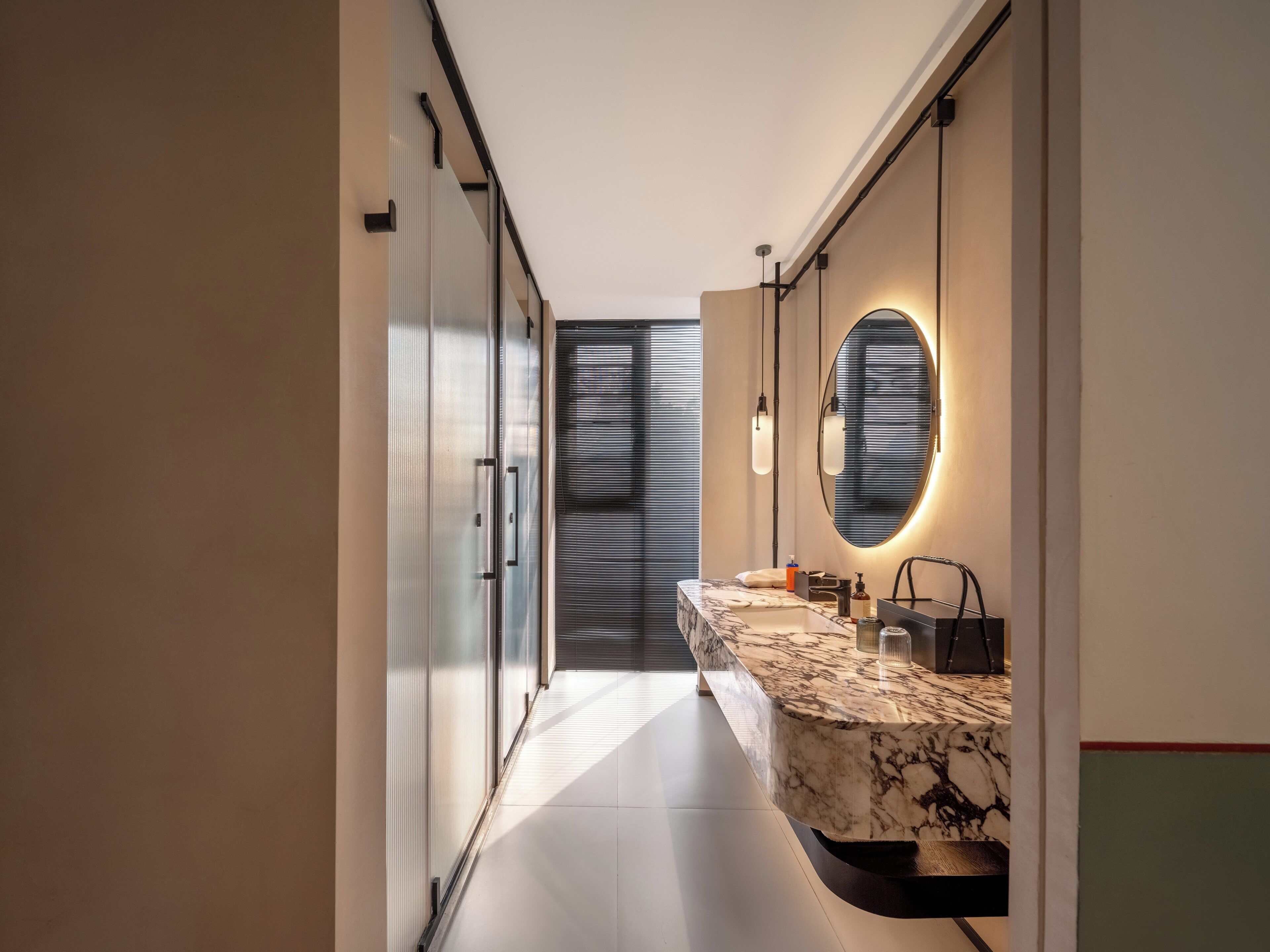 Een moderne badkamer met een marmeren wastafelmeubel, een grote spiegel en een strak design.