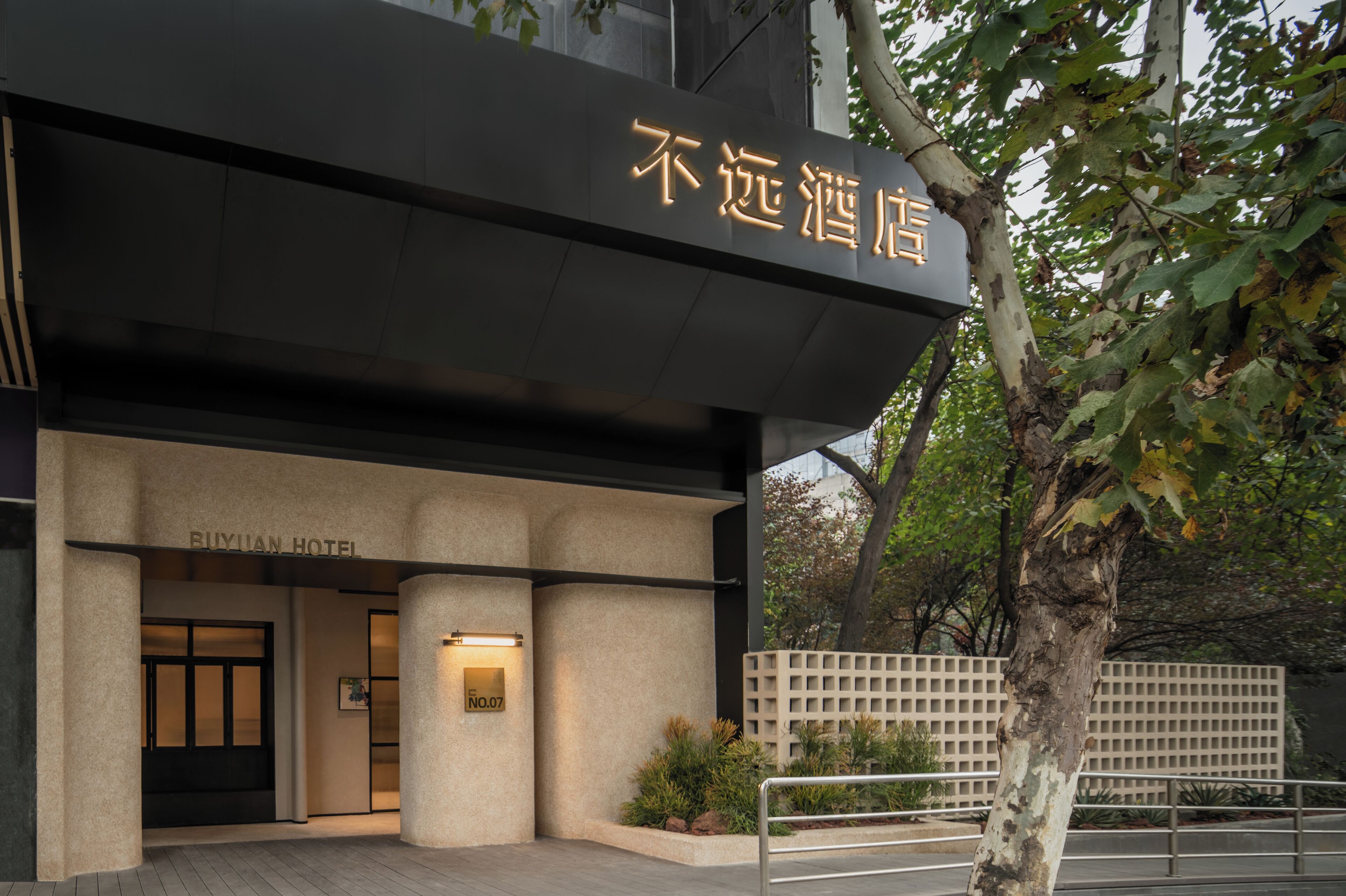 The exterior of Buyuan Hotel with a modern facade, a signboard, and a well-maintained entrance area.