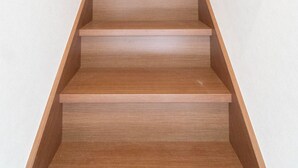 A wooden staircase with a handrail and a wall-mounted light fixture. - HANASTAY KAWA (Osaka)