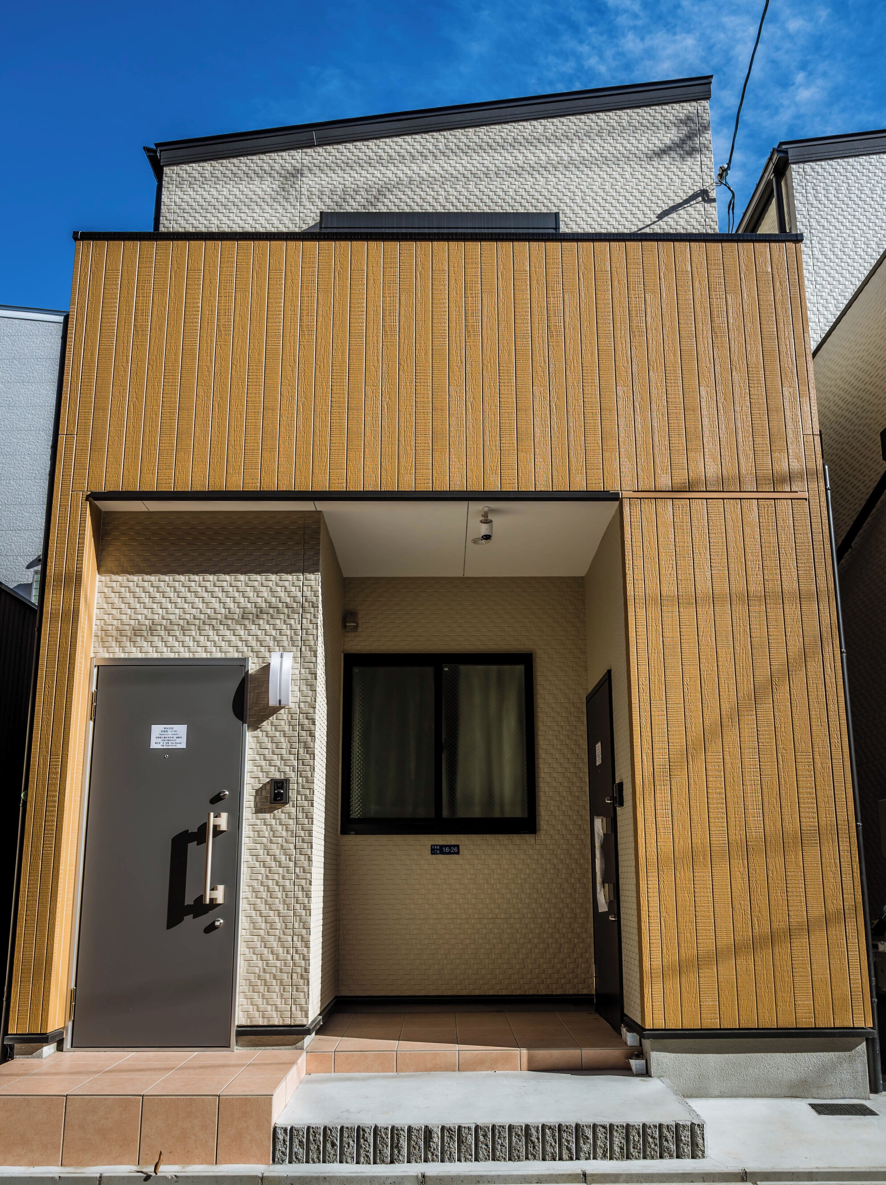 A modern building with a wooden facade, a large window, and a door with a sign.