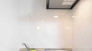 A kitchen with a stainless steel sink, a built-in oven, and a range hood above the stove. - HANASTAY KAWA (Osaka)