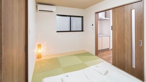 A room with a bed, a window, an air conditioner, and a wardrobe. - HANASTAY KAWA (Osaka)