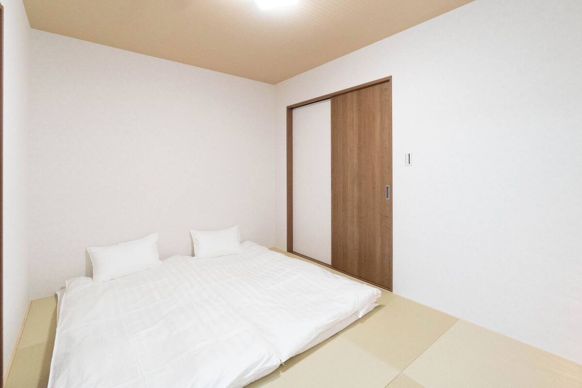 A bedroom with a bed, a wooden wardrobe, and a light-colored floor.