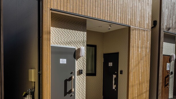 A modern building with a brick facade and a wooden panel entrance. - HANASTAY KAWA (Osaka)