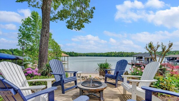Une terrasse au bord du lac, avec des fauteuils Adirondack, un foyer et une vue sur le lac.