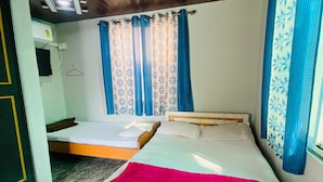 Une chambre avec deux lits en bois, un ventilateur de plafond et des rideaux bleus.