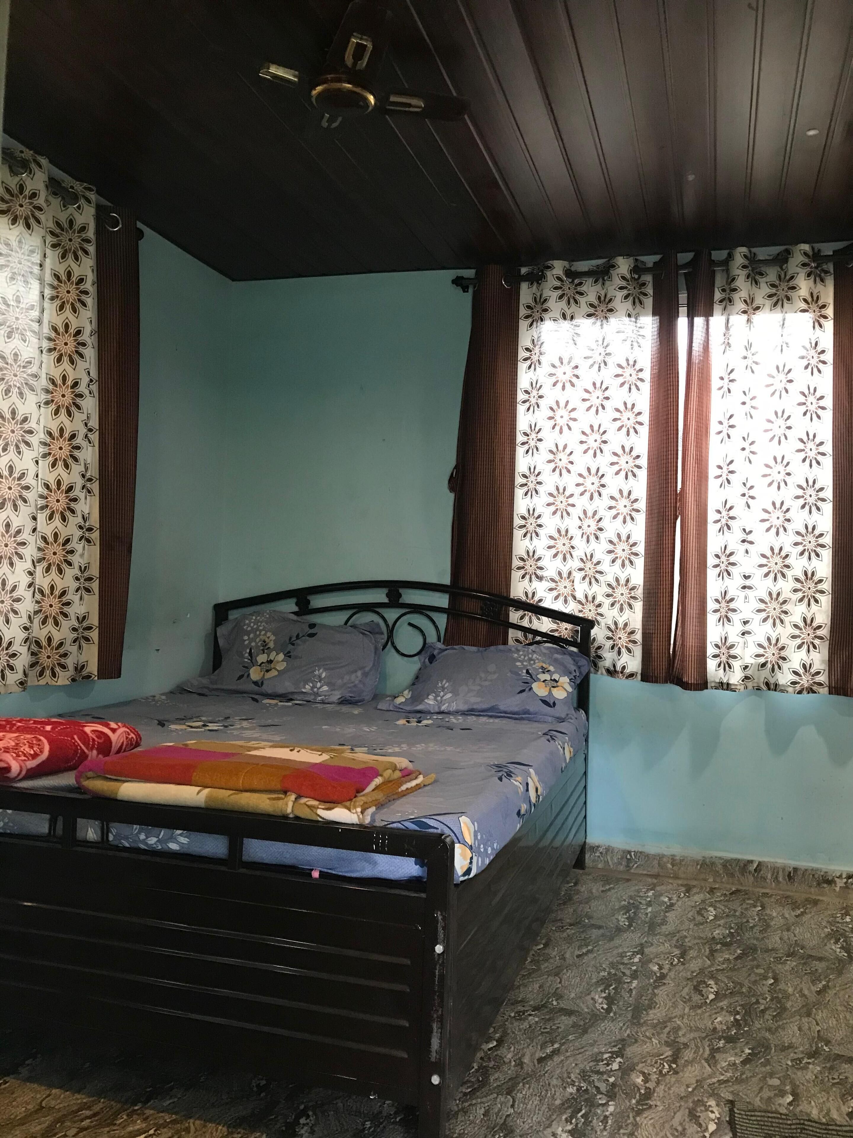 A bedroom with a bed, curtains, and a ceiling fan.