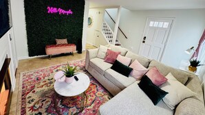 Ein modernes Wohnzimmer mit grüner Wand, einer Couch, einem Couchtisch und einer Treppe im Hintergrund.