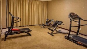 Quarto com esteira, elíptico e aparelho de musculação.
