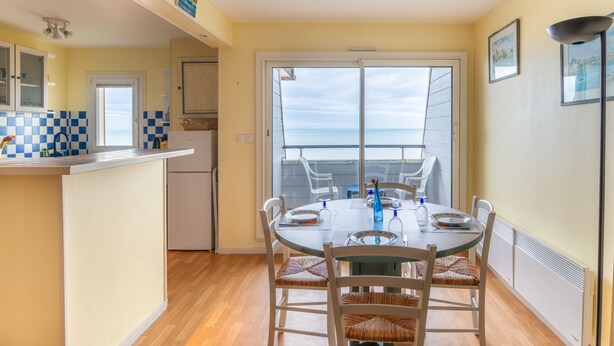 Un comedor con vista al mar, una cocina con baldosas de cuadros y un balcón con vistas.