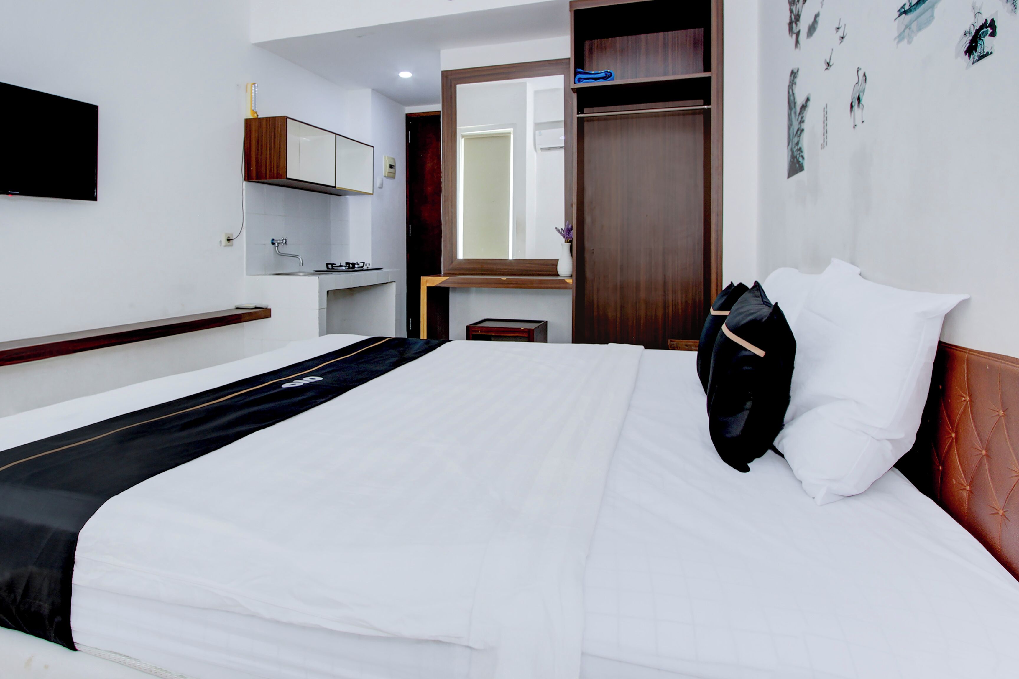 Ein Hotelzimmer mit einem großen Bett, einem Holzkopfteil, einem Nachttisch, einem Spiegel und einem Kleiderschrank.