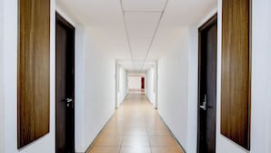 Un passadís llarg i estret amb portes a banda i banda, que condueix a una habitació al final.