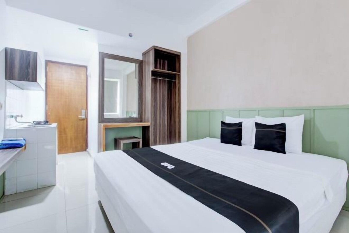 A hotel room with a bed, a desk, a mirror, and a wardrobe.