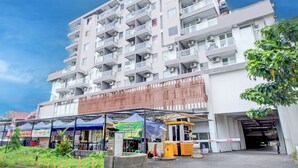 Un edifici residencial de diverses plantes amb balcons, una entrada tancada i zones d'estar a l'exterior.