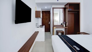 Habitació d'hotel amb llit, escriptori, armari, mirall i televisió penjada a la paret.