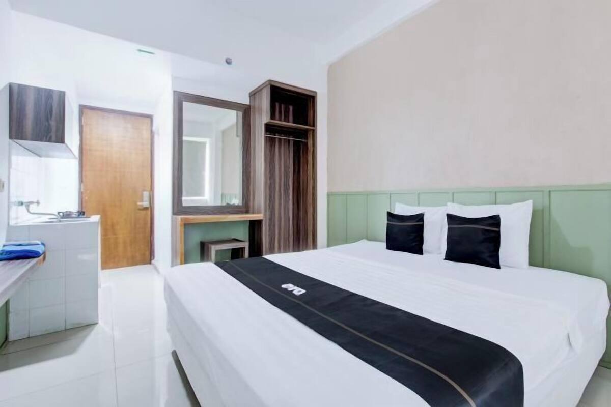 Una habitación de hotel con una cama, un escritorio, un espejo y un armario.