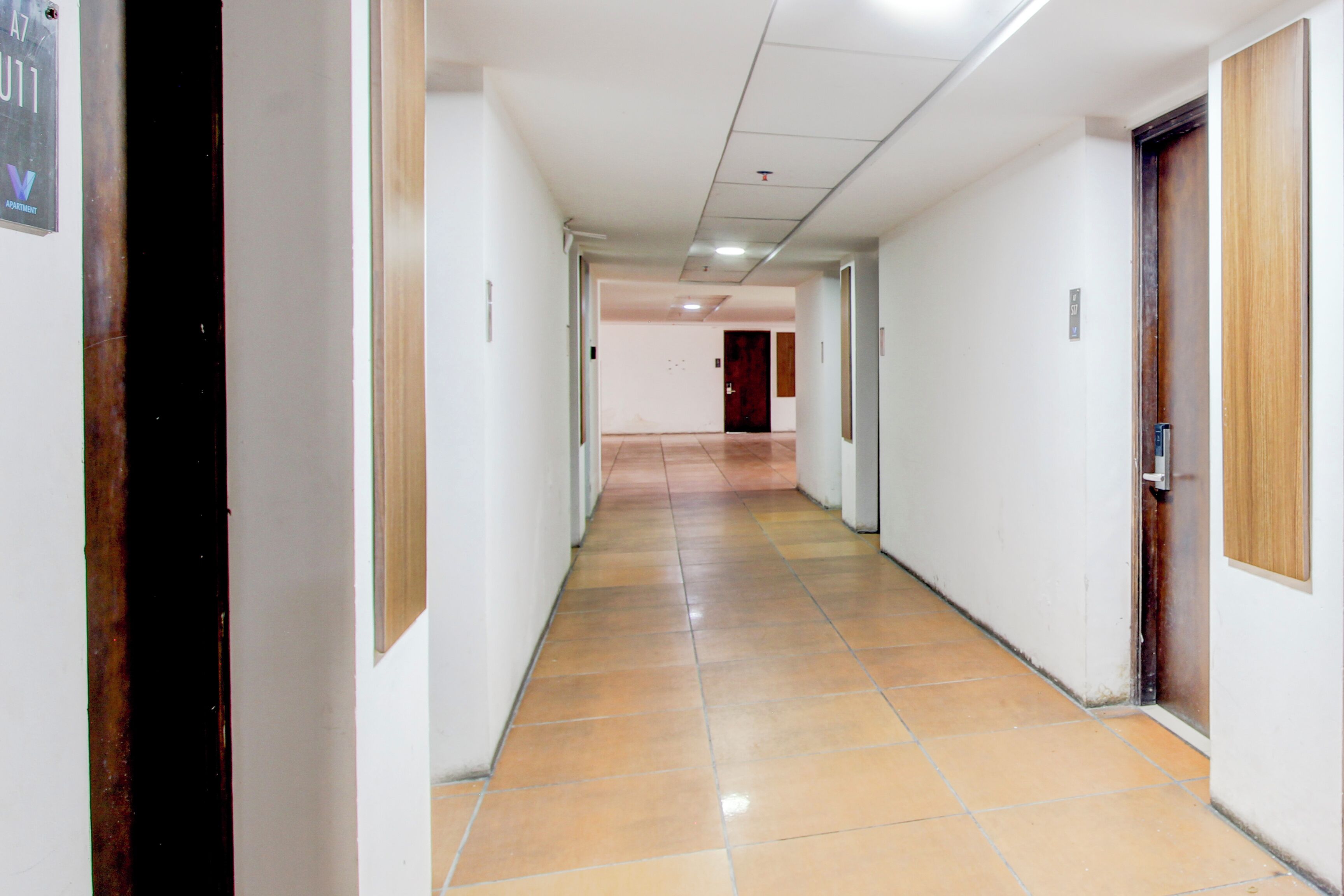 A long, narrow hallway with tiled flooring and doors on both sides.