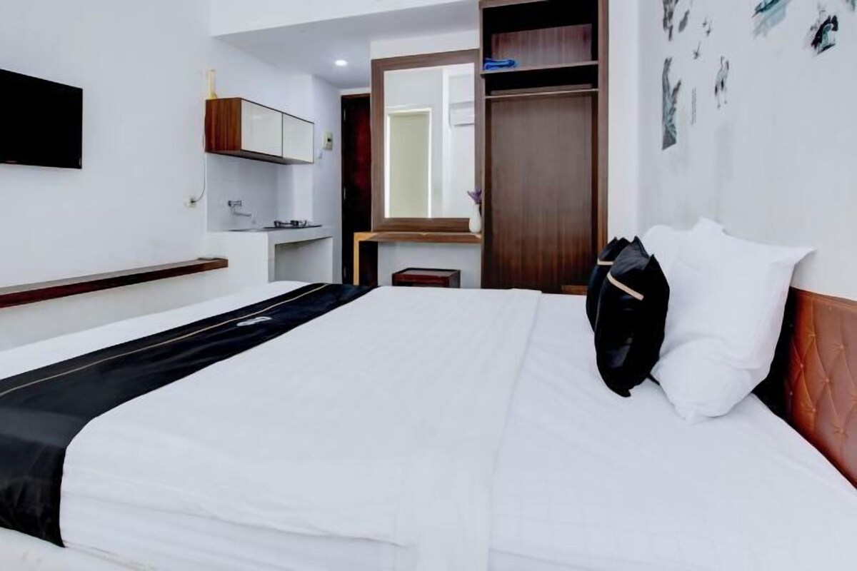 Una habitación de hotel con cama, armario, espejo y una mesita.